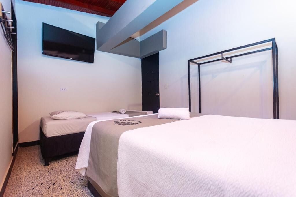 A hotel room with two beds, a TV mounted on the wall, and a door.