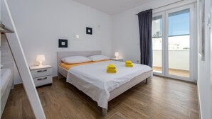 A hotel room with a bed, two bedside tables, a window with curtains, and a view of the outside.