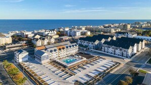 A coastal hotel with a swimming pool, multiple buildings, and a view of the sea.