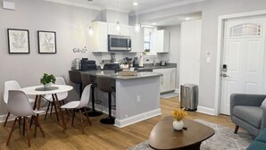 Une cuisine moderne avec des meubles blancs, un îlot central et des luminaires suspendus.