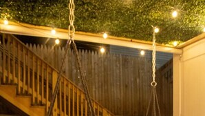 Deux fauteuils suspendus avec des coussins, un escalier en bois et une clôture en arrière-plan.