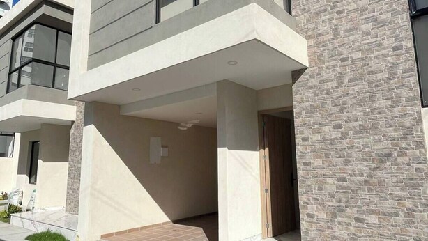 Un edificio residencial moderno de varios pisos con tejado plano, ventanas grandes y fachada de piedra.