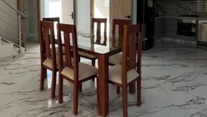 Un comedor amplio con suelo de mármol y sillas de madera.