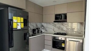 Una cocina moderna con un refrigerador de acero inoxidable, un microondas y una estufa a gas.