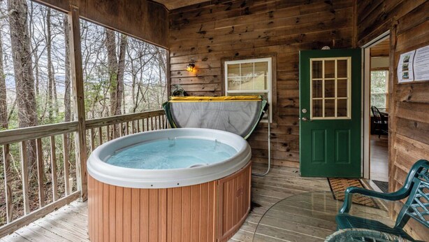 A wooden cabin with a hot tub, a door, and a bench.