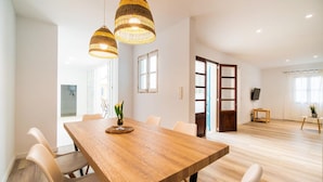 Un comedor moderno con una mesa de madera, sillas blancas y dos lámparas colgantes de mimbre.
