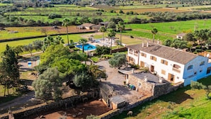 Una villa con piscina, muros de piedra y vistas a campos circundantes.