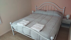 A neatly made bed with a white duvet and two folded towels on the footboard. - Little House (Bracciano)
