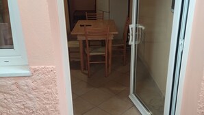 A small dining area with a table and chairs, a sliding glass door, and a window. - Little House (Bracciano)