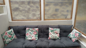 A grey sofa with floral cushions and a window with a stone-like pattern. - Little House (Bracciano)