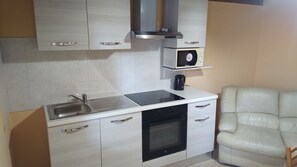 Een oven, een koffiezetapparaat/waterkoker, kookgerei, borden en bestek