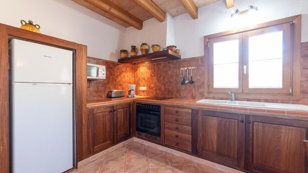 Une cuisine avec des meubles en bois, un réfrigérateur blanc, un four à micro-ondes, un lave-vaisselle et une fenêtre avec un évier.