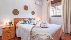 A neatly arranged hotel room with a wooden bed, two bedside tables with lamps, a potted plant, and decorative wall hangings. - Villa Hermanas Algodonales by Ruralidays (Cádiz)