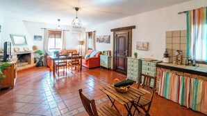 A spacious living area with a fireplace, dining table, and orange sofa. - Villa Hermanas Algodonales by Ruralidays (Cádiz)