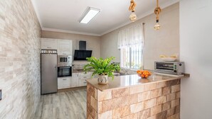 A modern kitchen with a central island, built-in appliances, and a potted plant. - Los tres picos Prado del Rey by Ruralidays (Cádiz)