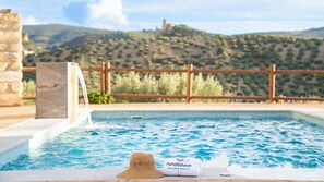 A pool with a wooden fence and a stone wall, a hat, and a towel on the edge.