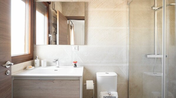 A modern bathroom with a wooden vanity, a glass shower enclosure, and a visible toilet.