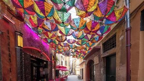 Une rue étroite, agrémentée de décorations colorées suspendues et dotée de tables en plein air.