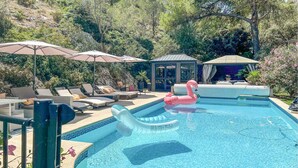 A swimming pool with lounge chairs and umbrellas, surrounded by greenery. - Pet friendly home in CAVAILLON (CAVAILLON)