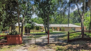 A building with a covered outdoor area, surrounded by trees and a fenced entrance.