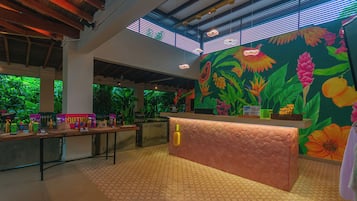 Een receptie met een balie, een groot bloemenmural en uitzicht op groen door de ramen.