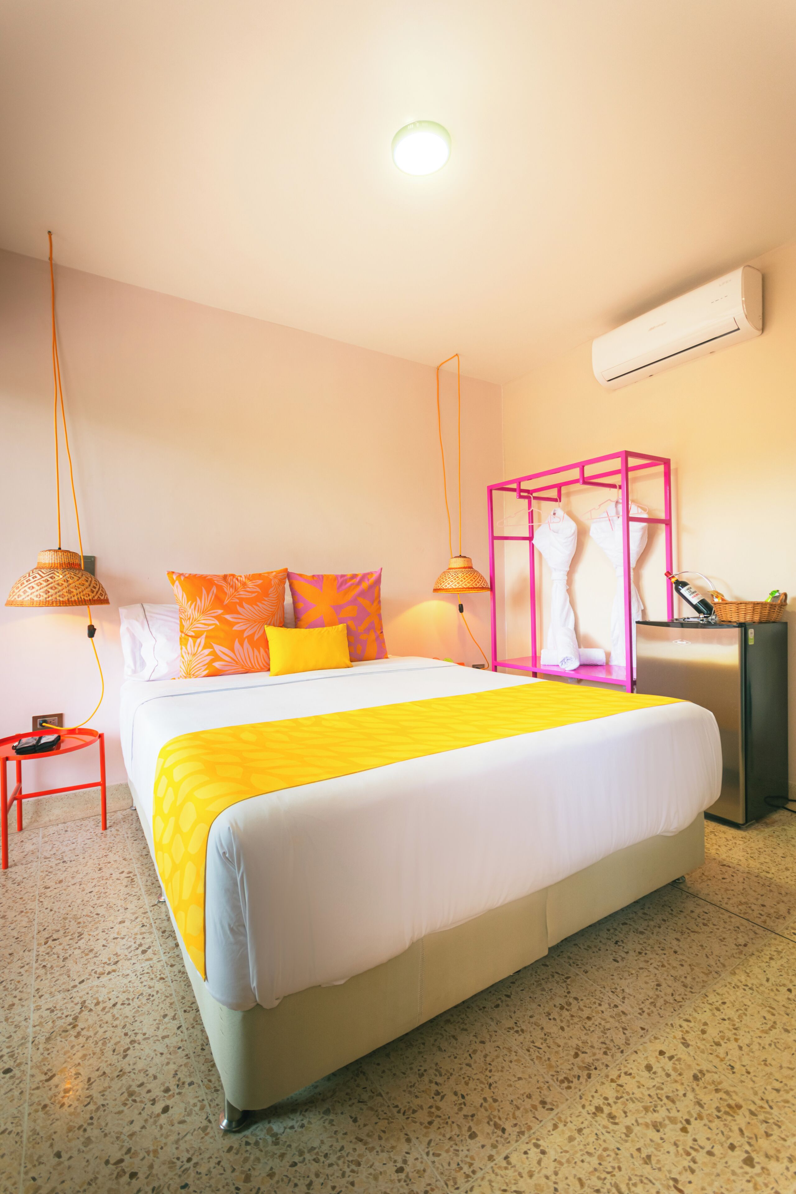 Una habitación de hotel con cama, mesita de noche, lámpara, armario y aire acondicionado.