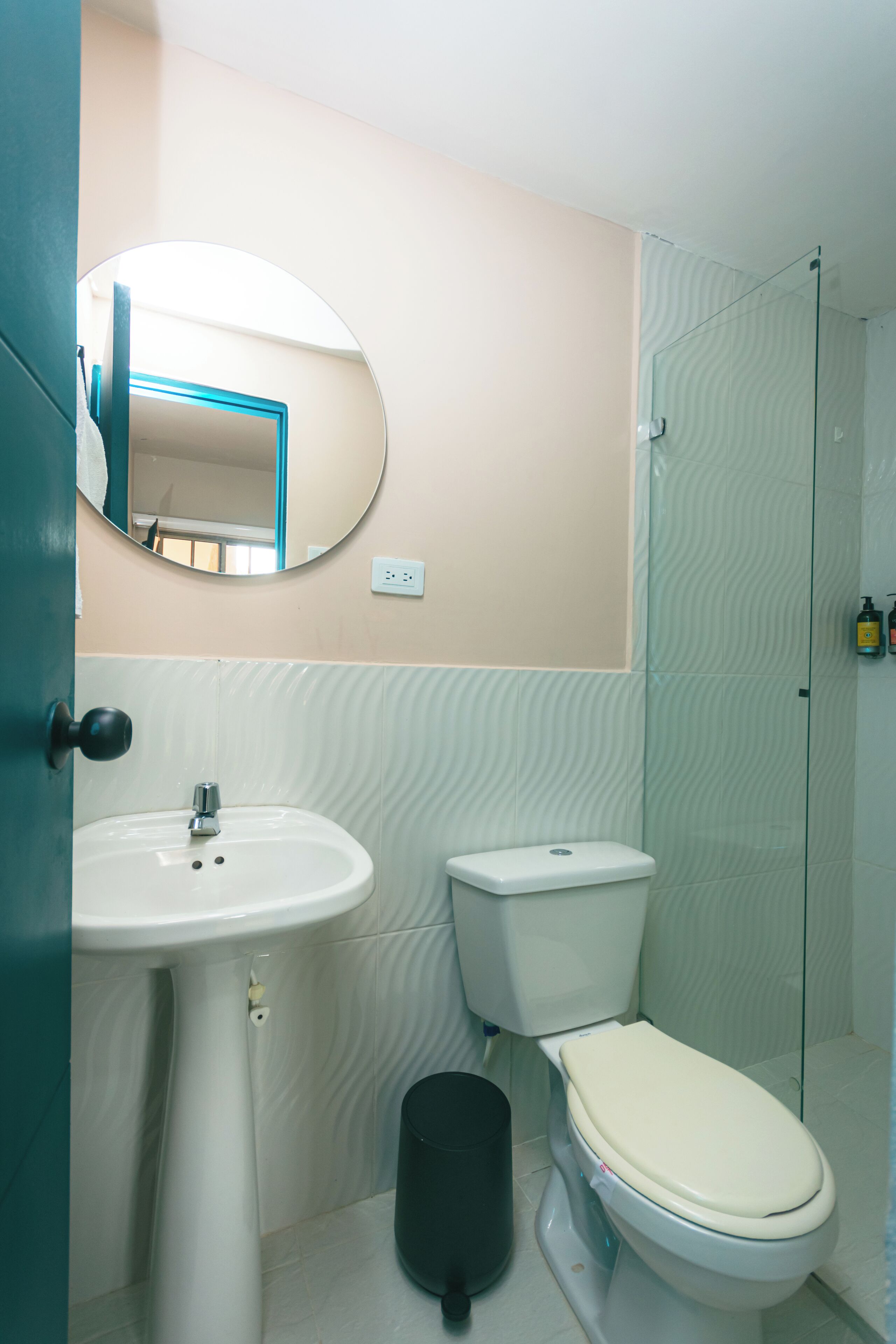 A bathroom with a white sink, toilet, and glass shower enclosure.