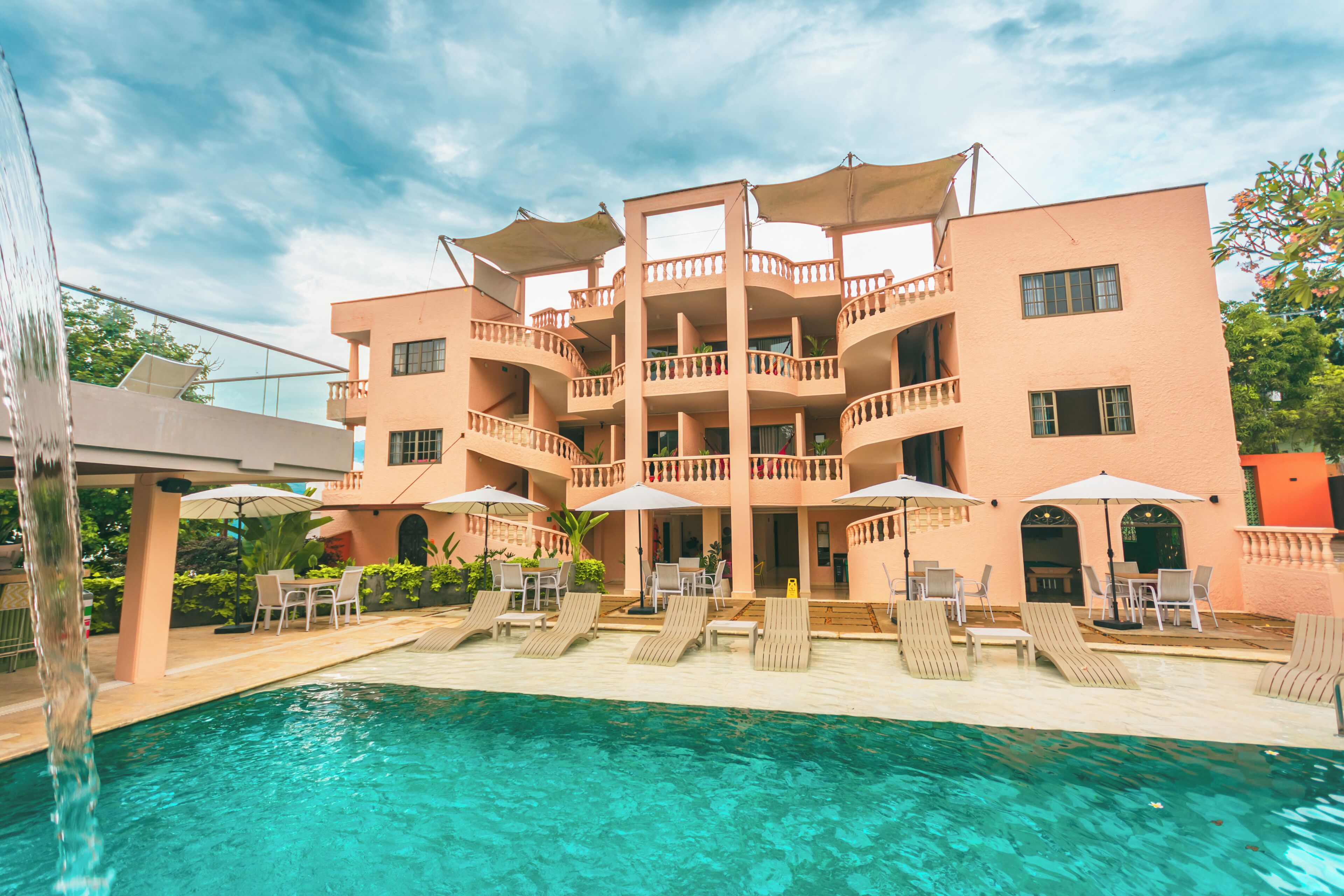 A multi-story hotel with a swimming pool, outdoor seating, and a covered terrace.