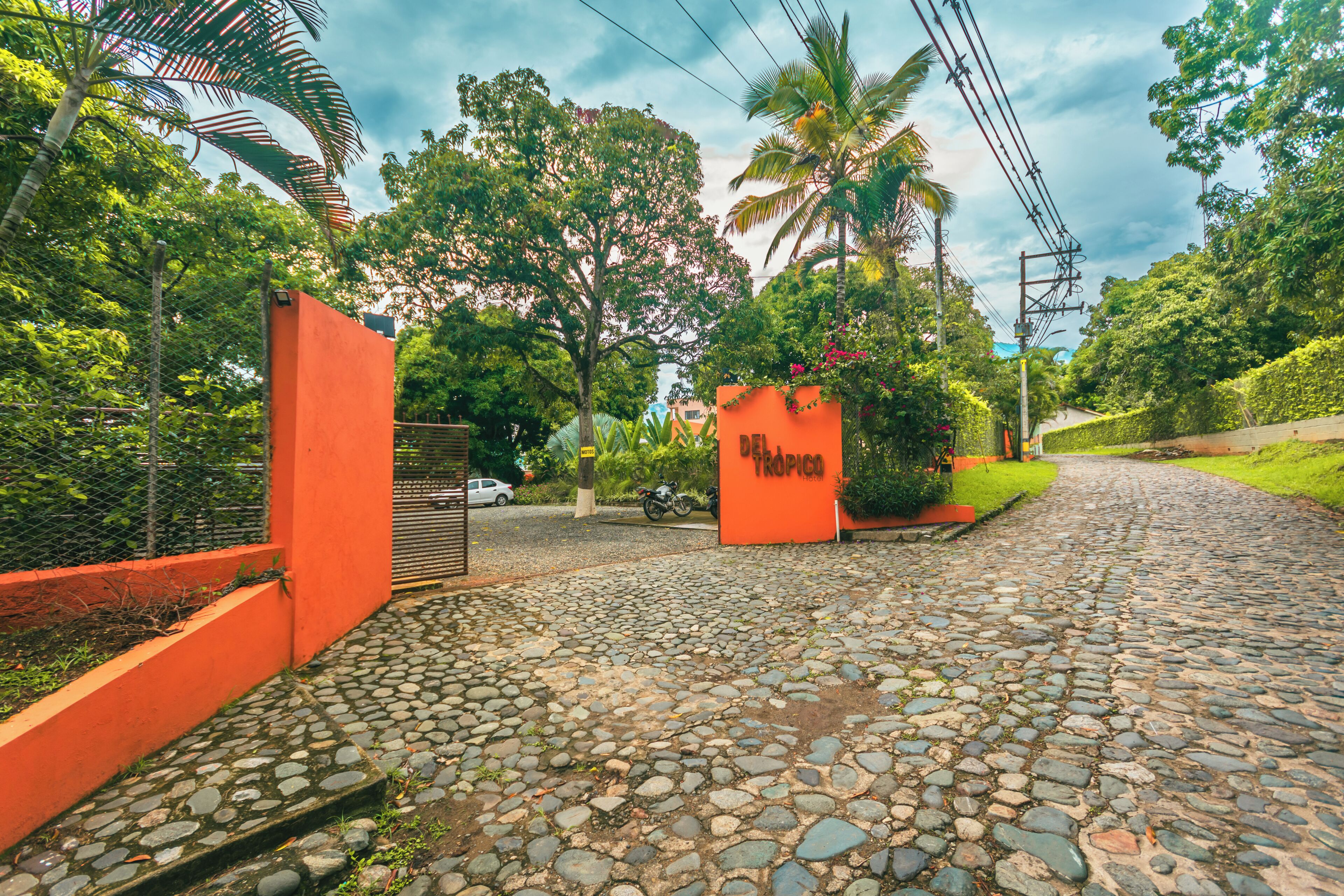 A cobblestone pathway leading to a building with an orange wall and a sign reading 'TROPICO.'