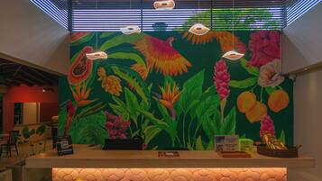 A reception desk with a tropical mural, a patterned floor, and a ceiling with exposed beams and lighting fixtures.
