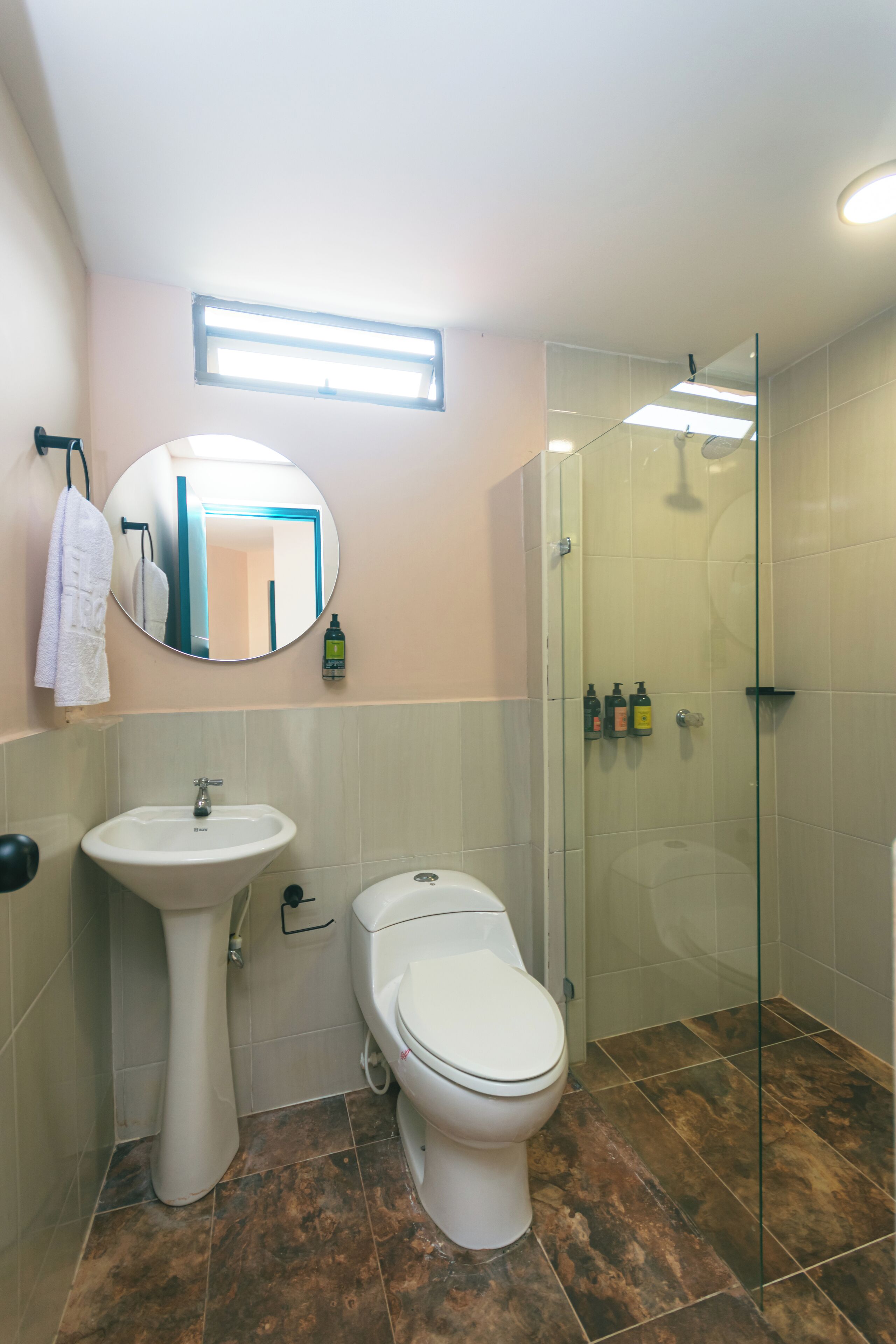Une salle de bain avec un lavabo sur colonne, des toilettes et une cabine de douche en verre.
