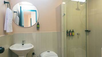 Une salle de bain avec un lavabo sur colonne, des toilettes et une cabine de douche en verre.