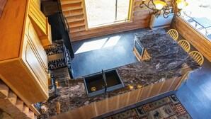 A kitchen with a marble countertop, wooden cabinets, and a built-in stove. - Destination Alaska Charters - Cabin 1 (Homer)