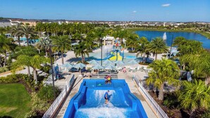 Ein Wasserpark mit einem großen Pool, Palmen und Blick auf einen See sowie Häuser im Hintergrund.