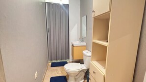 Um corredor estreito com vaso sanitário, pia e guarda-roupa.