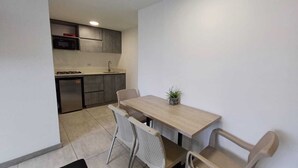 A compact kitchen with a microwave, sink, and built-in oven. A dining table with four chairs is positioned in front of the kitchen. - Escape (Guatapé)