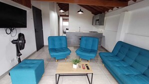 A living room with two blue sofas, a coffee table, and a TV mounted on the wall. - Escape (Guatapé)