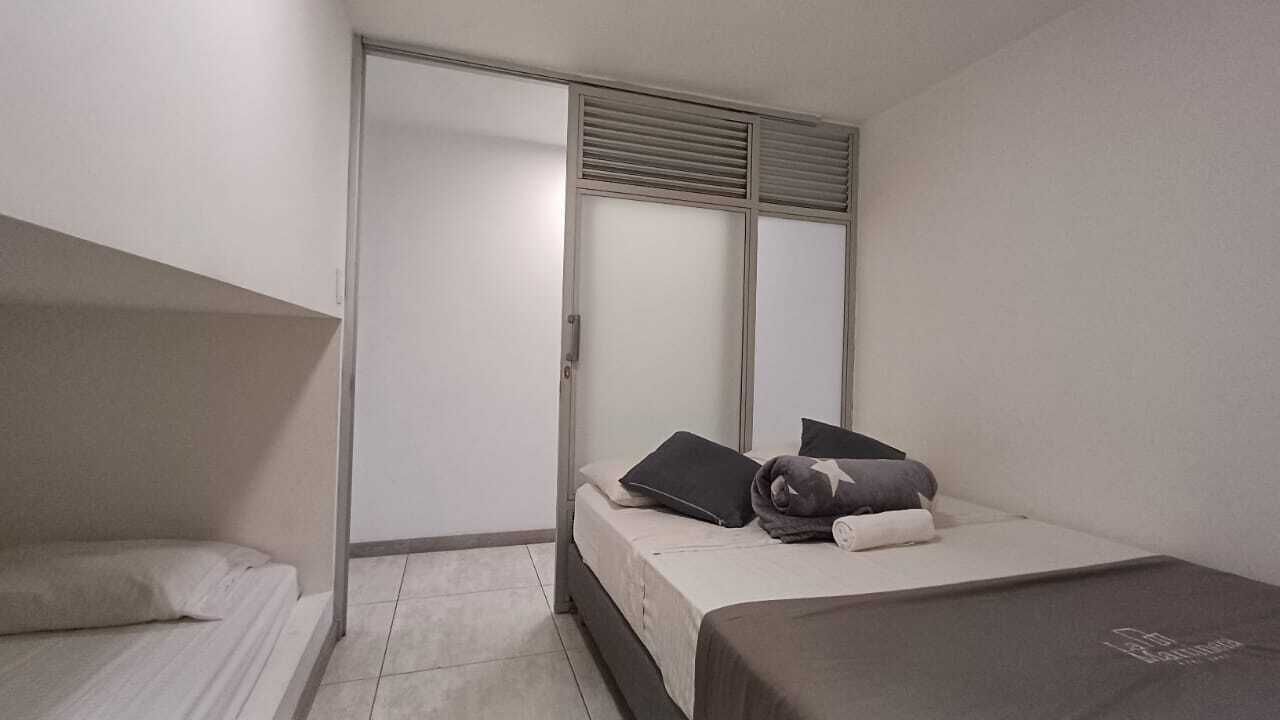 A small, well-lit bedroom with a single bed, a nightstand, and a closet with sliding doors.