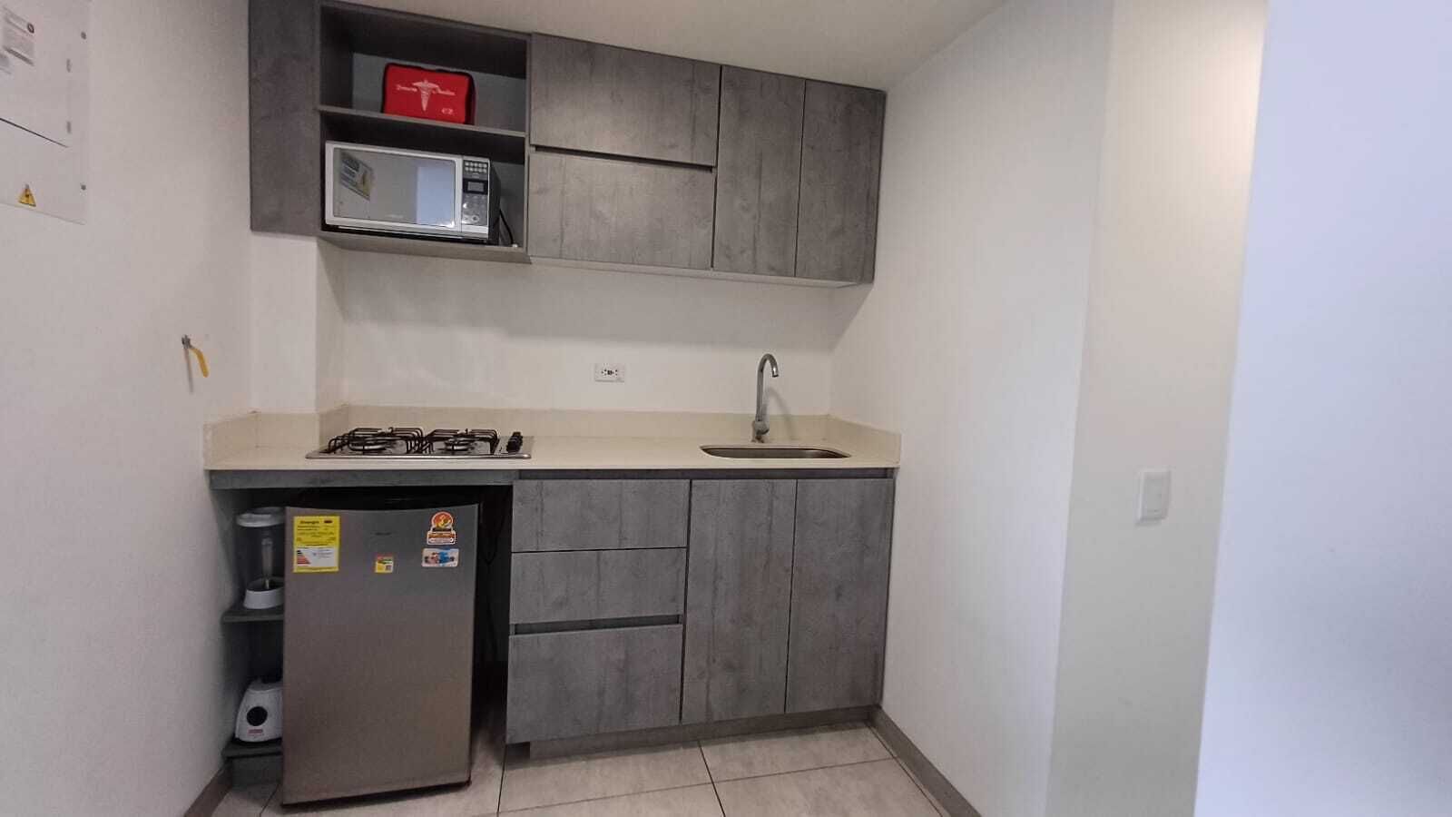 A compact kitchen with a gas stove, a microwave, and a sink.