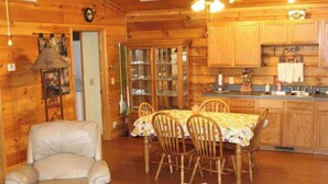 Un intérieur de chalet chaleureux avec un coin repas, des murs en bois et une cheminée.