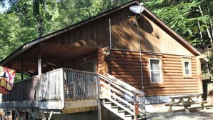 Une cabane en bois avec une véranda, une antenne parabolique et une table de pique-nique.