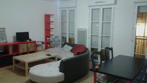 A living room with a sofa, a coffee table, a TV on a stand, a red shelf, and a fan. - 850 metres from Disney Land and Valley Village - 3 bedrooms - Sleeps 8 (Serris)
