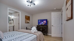 A bedroom with a bed, a television, a wardrobe, and a door. - Pet-Friendly 3BR Dayton Bungalow Near UD (Dayton)