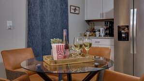 A modern kitchen with white cabinets, a stainless steel refrigerator, and a glass dining table with orange chairs. - Pet-Friendly 3BR Dayton Bungalow Near UD (Dayton)
