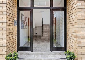 Enter a welcoming space with a glass door and steps leading up to a brick-lined entrance.