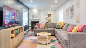Un salon moderne avec un canapé gris, une table basse et un téléviseur fixé au mur, qui diffuse différents services de streaming.