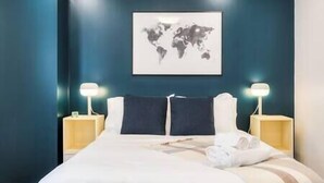 Une chambre d’hôtel avec un grand lit, deux tables de chevet et une œuvre d’art représentant une carte du monde accrochée au mur.