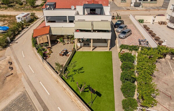 Un edificio moderno de dos pisos con techo plano, un patio cubierto y un césped bien cuidado.