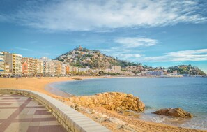 A coastal cityscape with a sandy beach, a rocky outcrop, and a hill with buildings. - Lovely home in Tordera (Tordera)