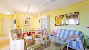 A living room with a glass coffee table, striped sofa, and armchairs. There is a dining area with a white cabinet and chairs. - Pet friendly apartment in El Campello (El Campello)